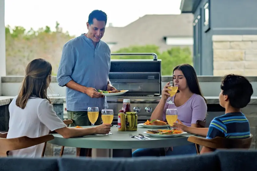 Family enjoying dinner outside from their propane grill